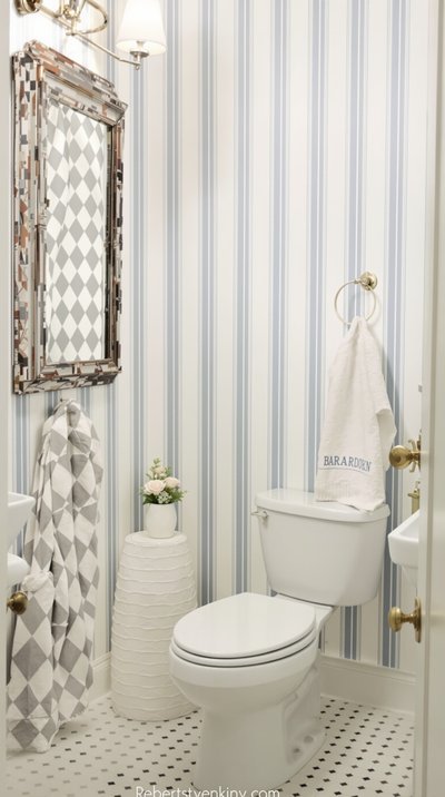 Gemütliches, im Landhausstil gehaltenes Badezimmer mit blau-weiß gestreifter Tapete.