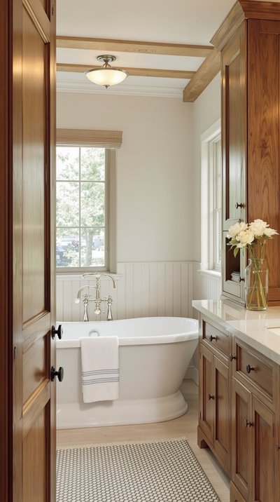 Badezimmer im Landhausstil mit einer freistehenden Klauenfußwanne und rustikalen Holzschränken