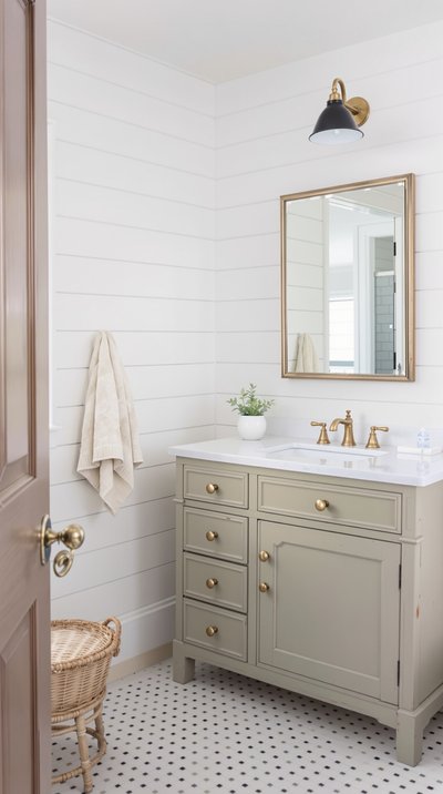 Bauernhaus-Badezimmer mit weißen Shiplap-Wänden, vintage Messingarmaturen und einem antiken Waschtisch