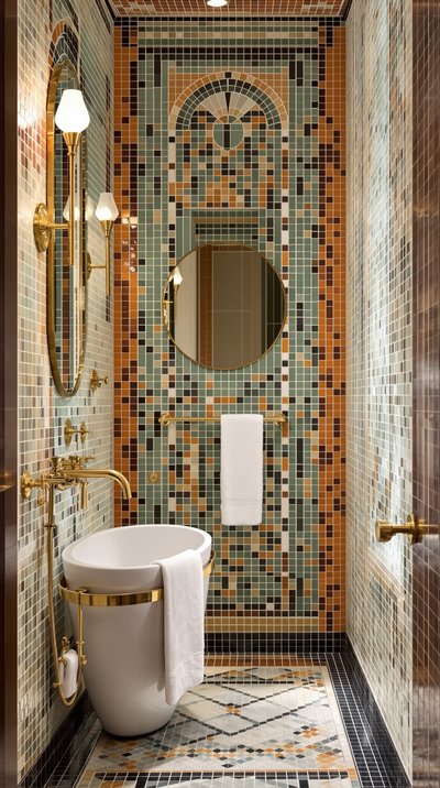 Badezimmer im Art-Deco-Stil mit bunten Mosaikfliesen und goldenen Armaturen