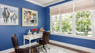 Traditionelles Homeoffice mit königsblauen Wänden, weißem Schreibtisch und Ledersessel.