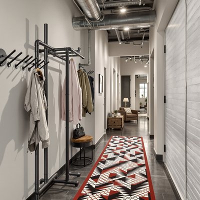 Industriekorridor mit Stahlrohren als Garderobe und kühnem, geometrisch gemustertem Teppich
