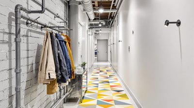 Industriekorridor mit Stahlrohren als Garderobe und kühnem, geometrisch gemustertem Teppich