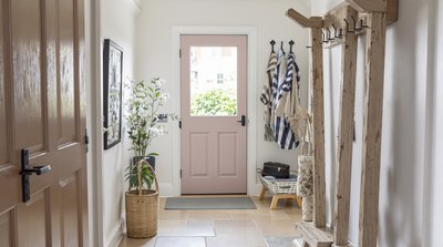 Helle Diele mit Steinboden und rustikalem Holzgarderobenständer.