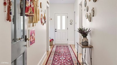 Bohemian-inspirierter schmaler Flur mit eklektischen, kleinen Spiegelakzenten und lebhaften Teppichen