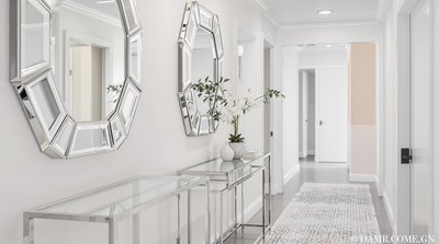 Zeitgenössischer heller Korridor mit geometrischen Spiegelakzenten und schlanker, metallener Konsolentisch