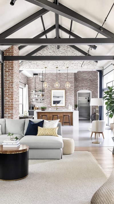 Geräumiges Wohnzimmer im offenen Konzept mit rohen Ziegelwänden und Akzenten aus Stahlträgern